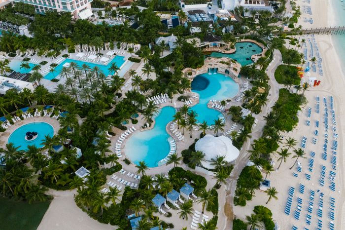 Aerial view of a beachfront resort with pools and palm trees