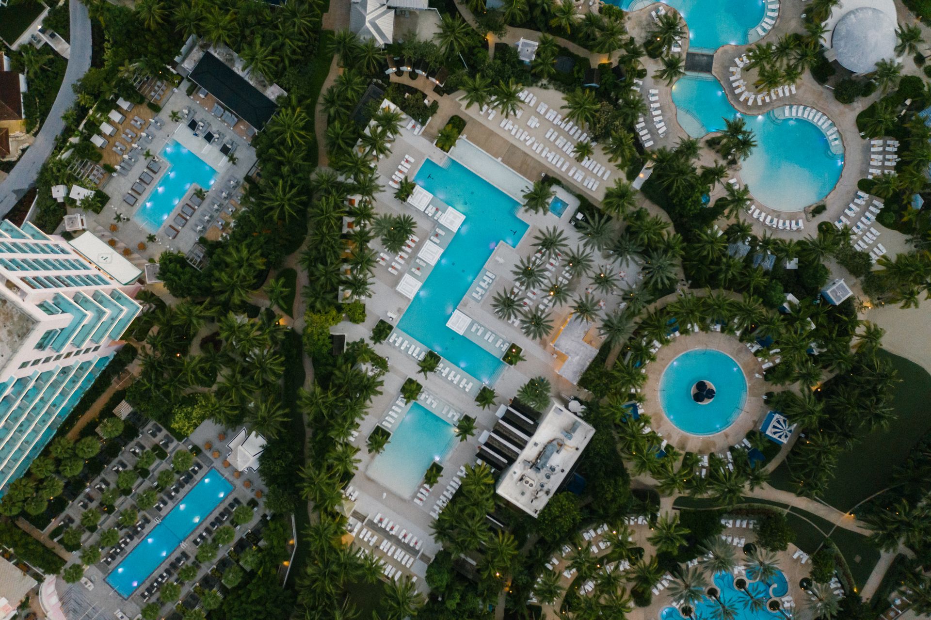 Aerial view of a lush Miami resort with multiple swimming pools framed by palm trees