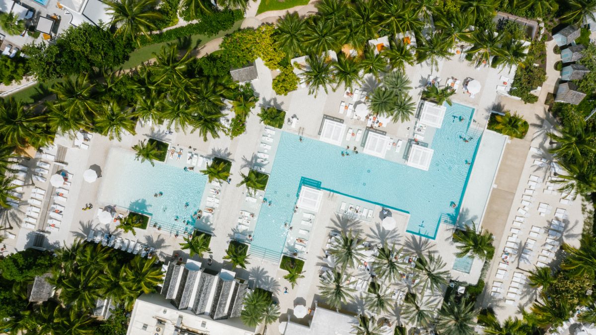 Aerial view of a luxury resort with multiple pools and palm trees