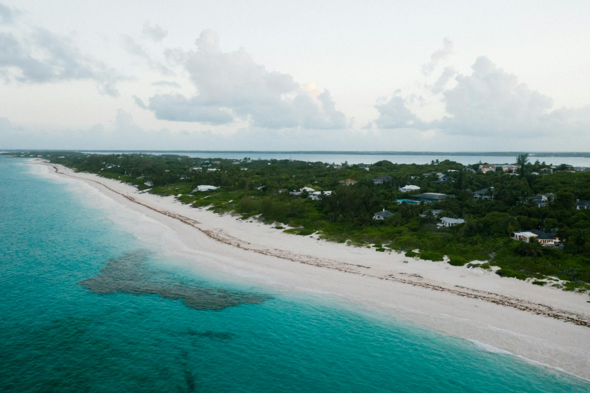 Tranquil aerial view of a lush tropical coast with turquoise waters and white sandy beach.