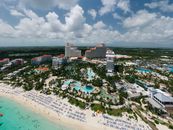 A stunning aerial shot of a luxury resort by the beach in the Bahamas, featuring pools and palm trees.