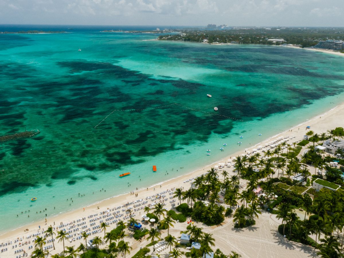 An aerial view of a tropical shoreline with clear turquoise water and white sand