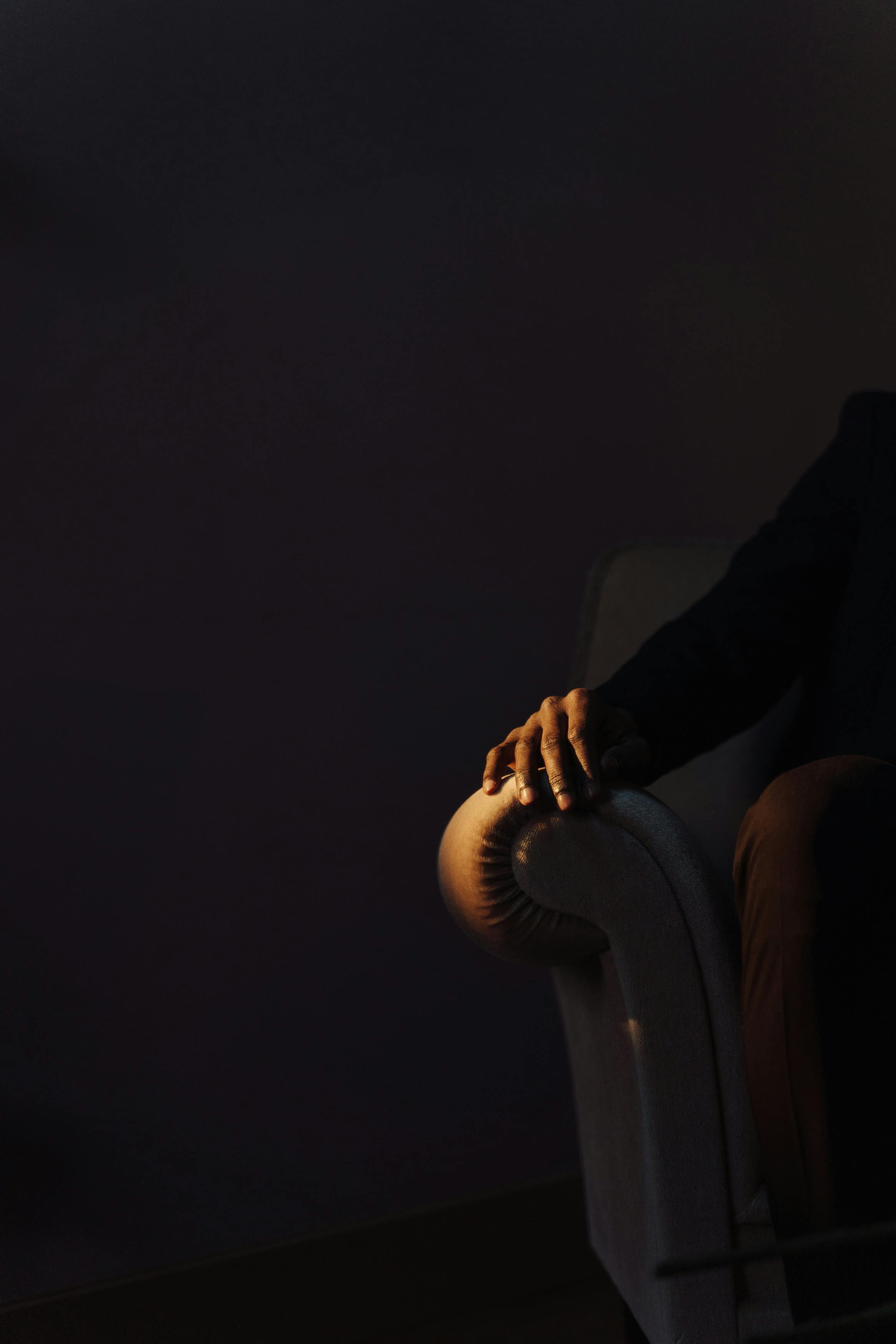 Free A mysterious hand rests on a sofa arm in a dark, moody setting with copy space. Stock Photo