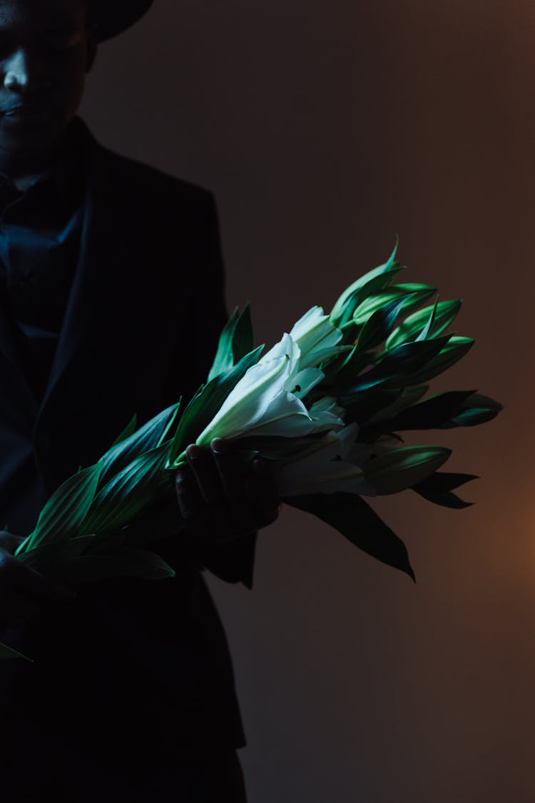 Man In A Suit Holding A Bouquet Of Lilies