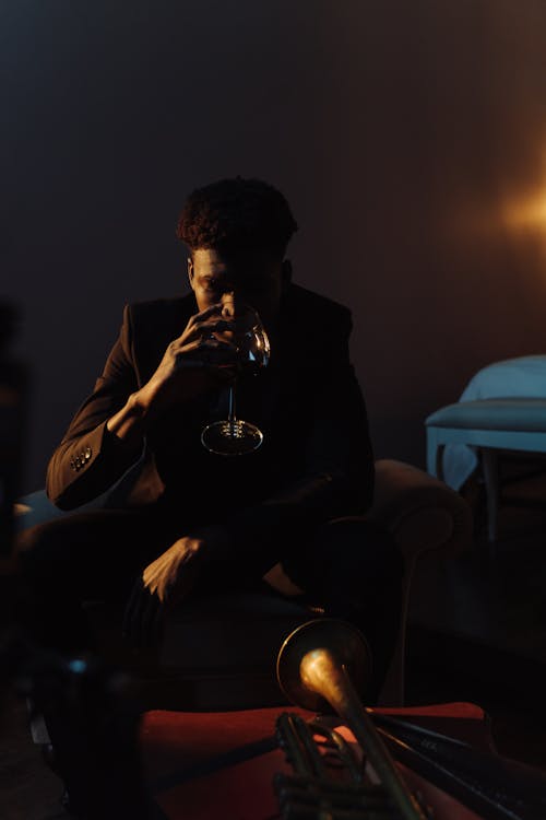 Man in Black Suit Sitting on Couch while Drinking Wine