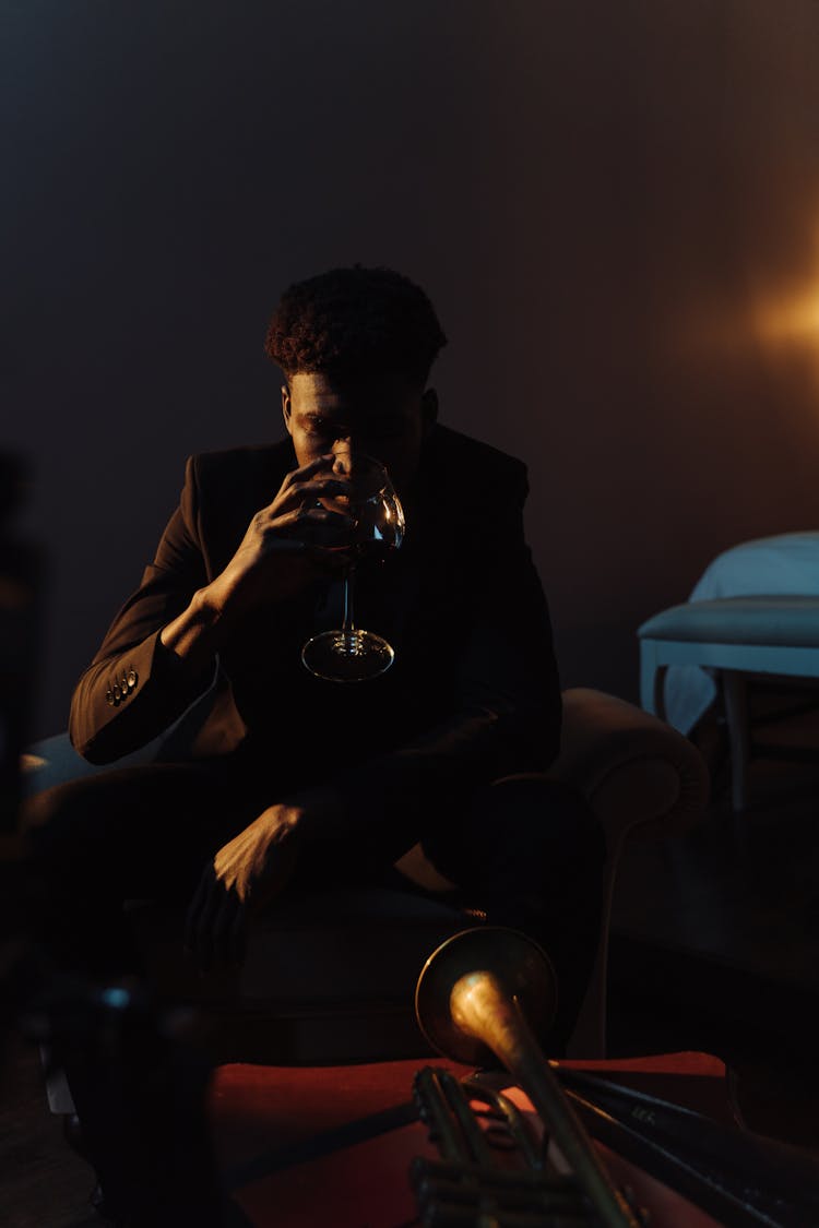 Man In Black Suit Sitting On Couch While Drinking Wine