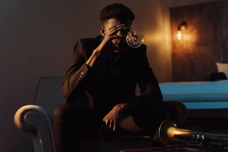 Man In Black Suit Sitting On Couch While Drinking Wine