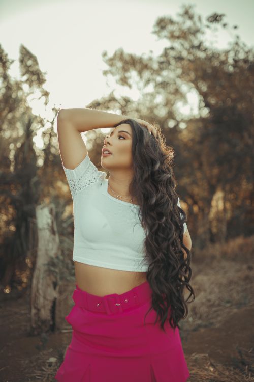 Free Young woman posing outdoors with hand on head, showcasing fashion style against nature backdrop. Stock Photo