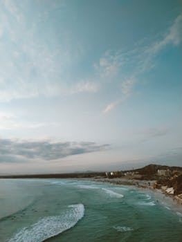Serene aerial view of a tranquil coastline with gentle waves at sunset. Perfect for relaxation themes.