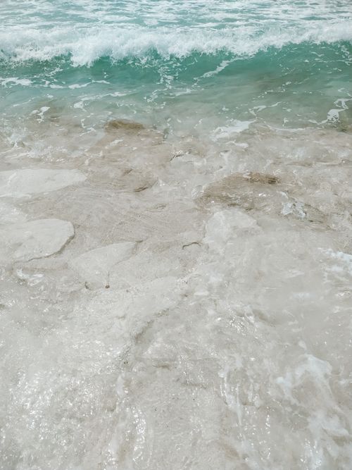 Free Close-up of clear turquoise waves washing over a serene sandy beach. Stock Photo