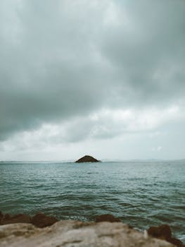 Captivating cloudy seascape with a tranquil ocean and distant island horizon, perfect for serene moments.