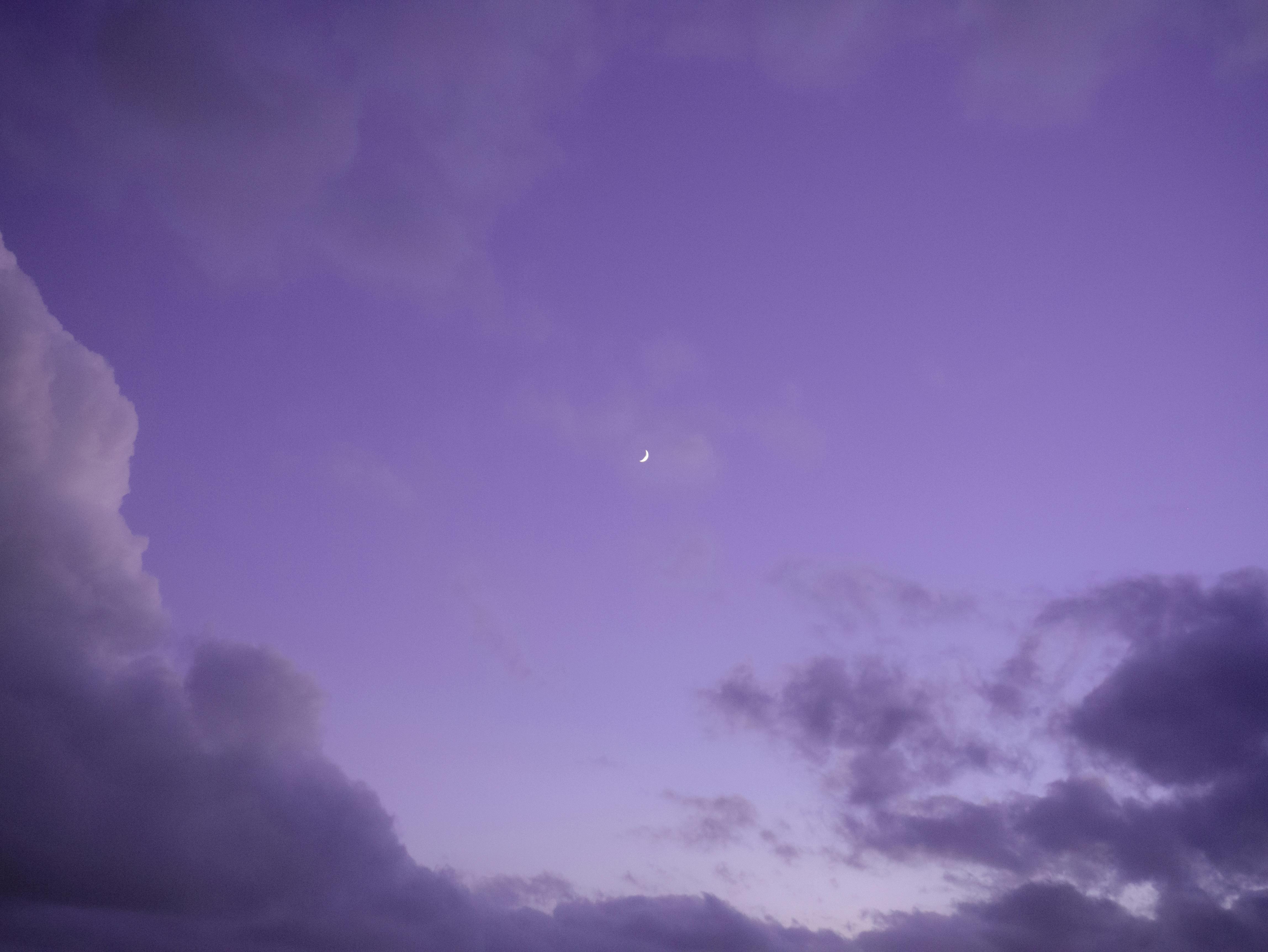 Crescent moon in purple sky with clouds 
