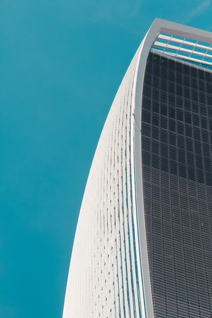 Modern skyscraper with a unique curved design against a blue sky in London, UK.