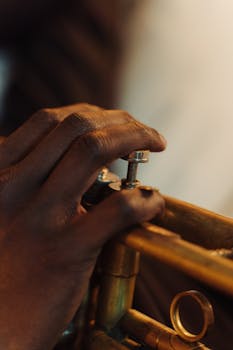 Detailed view of a musician's hand playing a brass trumpet, showcasing musical skill and precision.