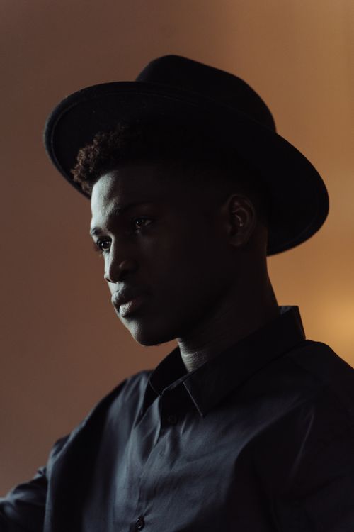 Free Portrait of a man wearing a hat, captured with moody lighting indoors. Stock Photo