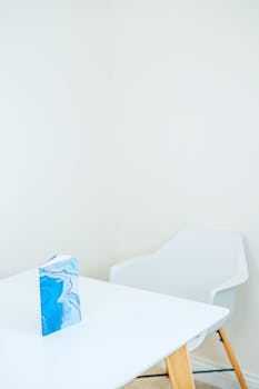 Modern white room with a blue notebook on a wooden table.