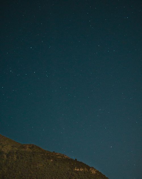 Free A tranquil night sky filled with stars above a mountain silhouette, perfect for nature enthusiasts. Stock Photo