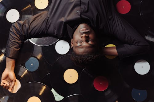 Man in Black Dress Shirt Lying Down on Vinyl Record 