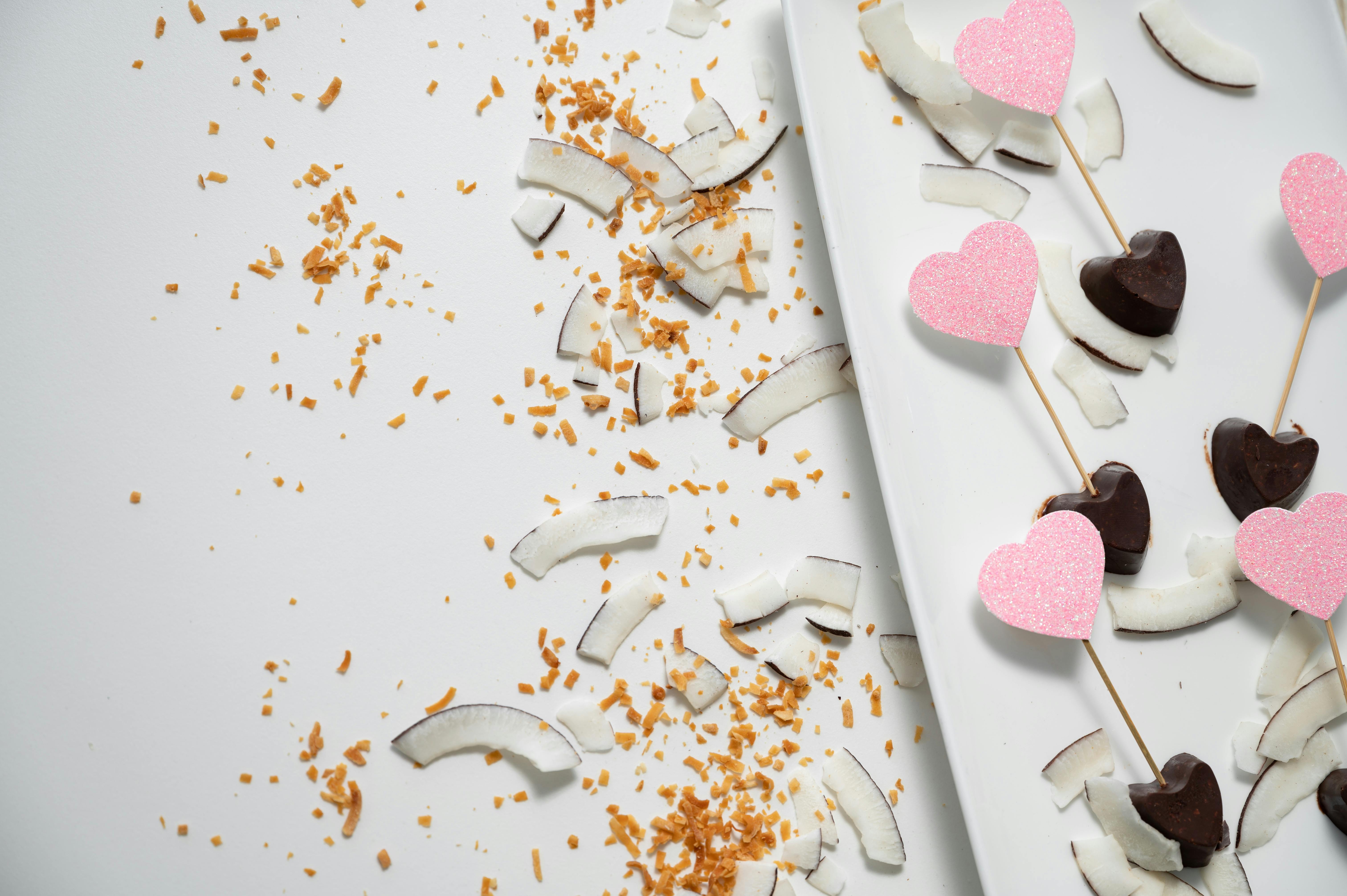 Artistic flat lay of heart-shaped chocolates and coconut slices, perfect for Valentine's Day.
