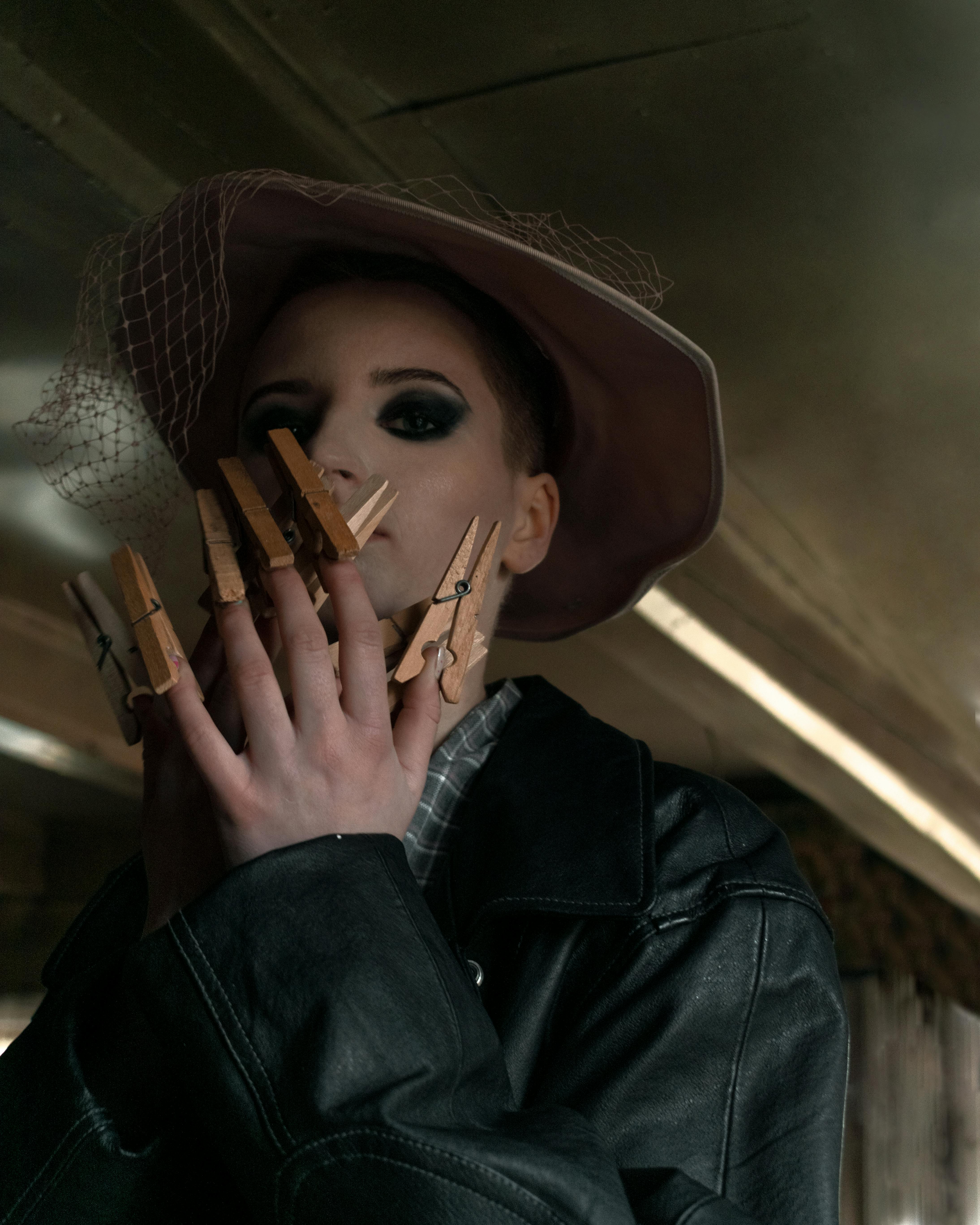 Artistic portrait of a woman with clothespins and dramatic eye makeup in a fashion setting.