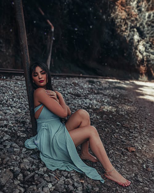 Woman in a Teal Dress Sitting on Stones