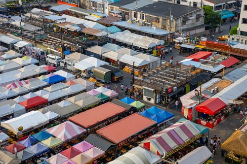 Free Colorful aerial view of bustling market stalls with diverse canopies and people shopping. Stock Photo