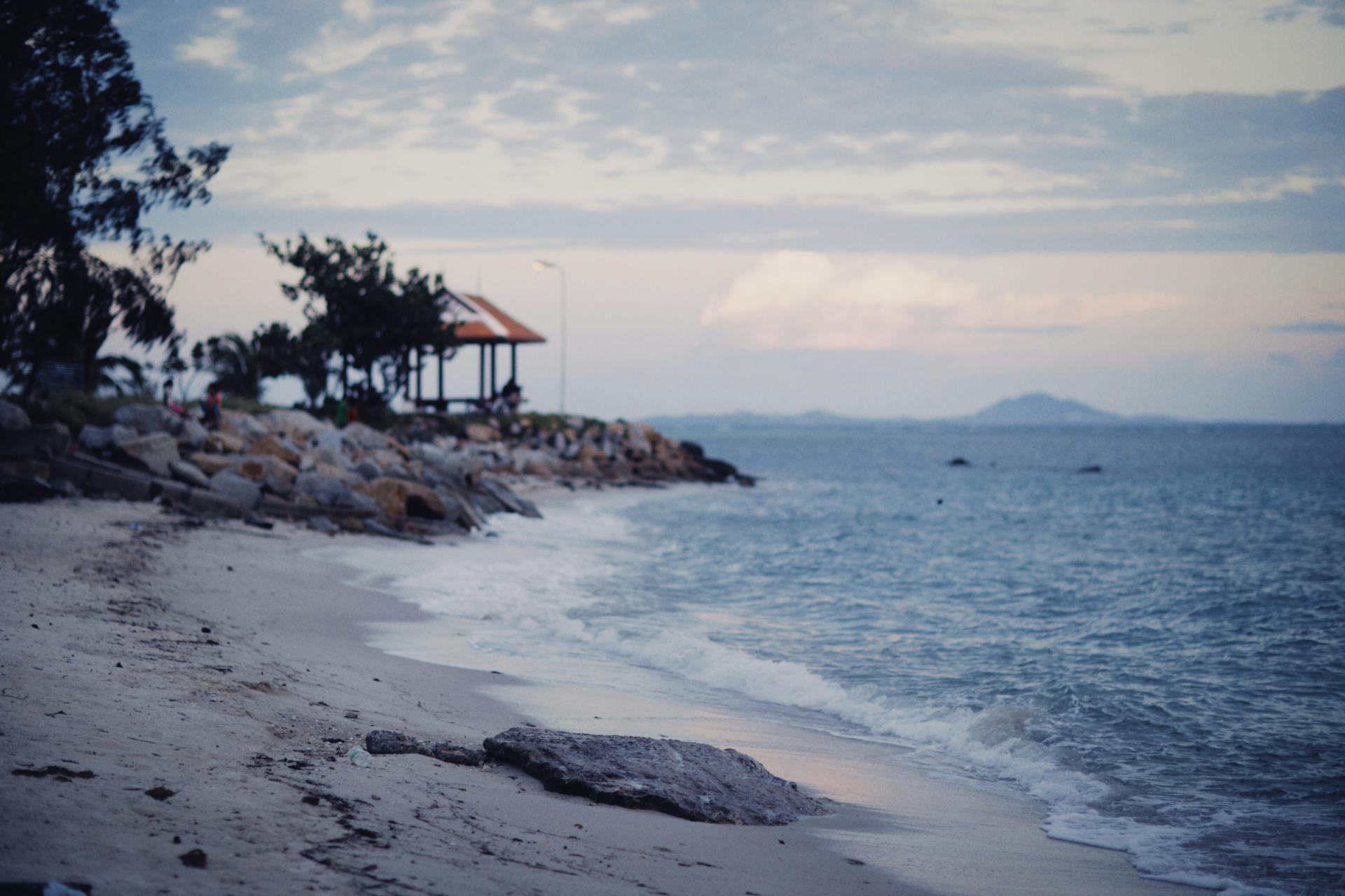 Beautiful serene beach during dusk with gentle waves and scenic clouds.