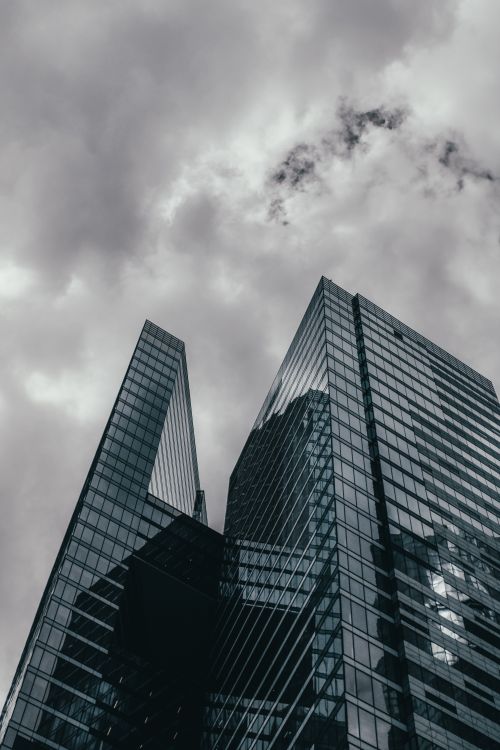 Free Gleaming skyscrapers reach into the cloudy sky, showcasing modern architecture. Stock Photo