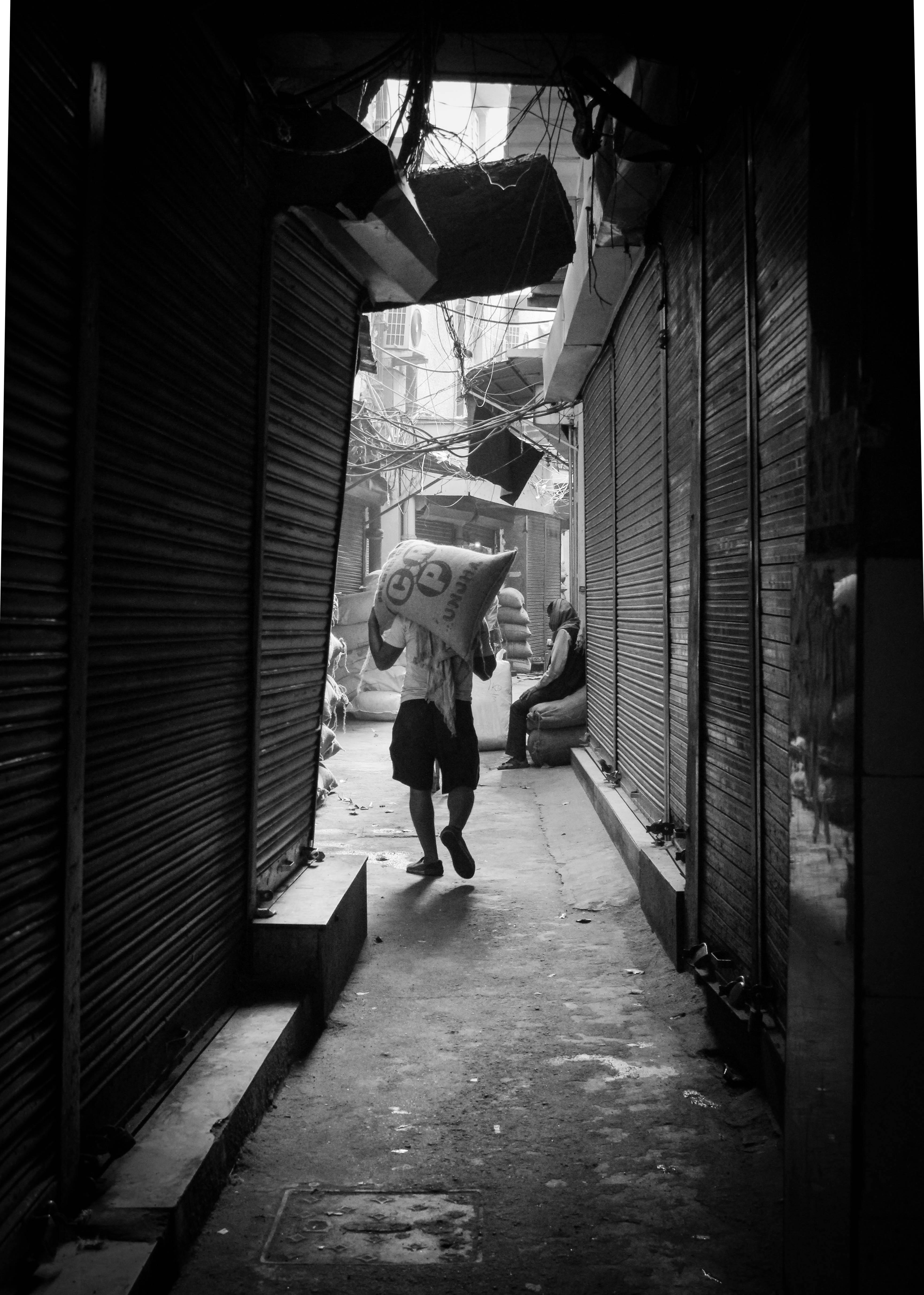 Grayscale Photo of Man Carrying Sack · Free Stock Photo