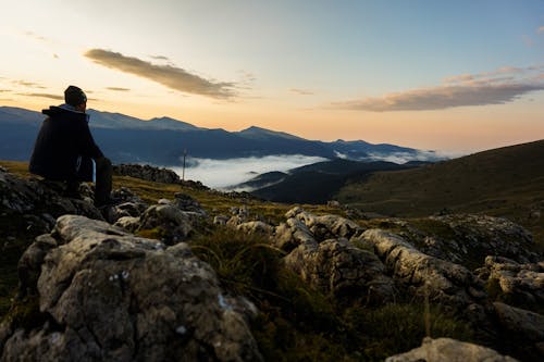 Free Person in Black Hoodie Sitting on Gray Stone Stock Photo