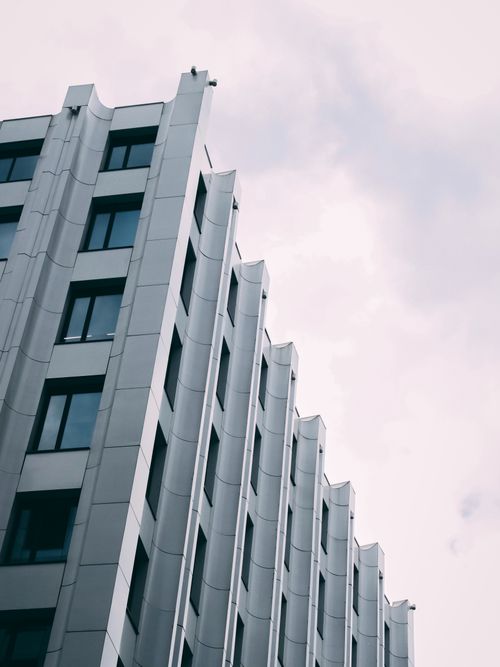 Free Architectural facade with geometric design set against a cloudy backdrop. Stock Photo