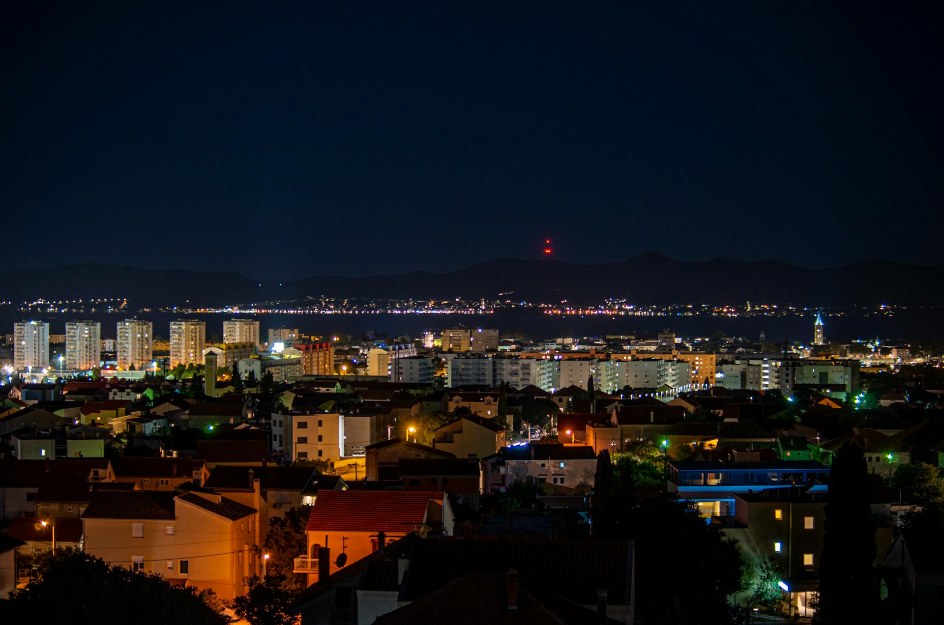 A breathtaking aerial view of Zadar cityscape illuminated at night, capturing vibrant urban life.