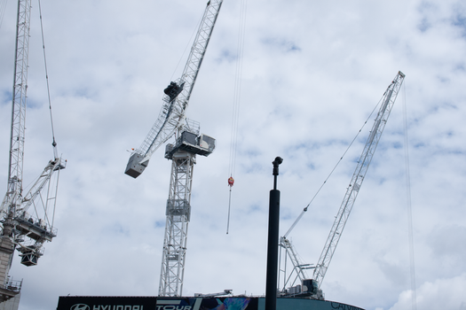Tower cranes rise against a cloudy sky, showcasing construction industry activity.