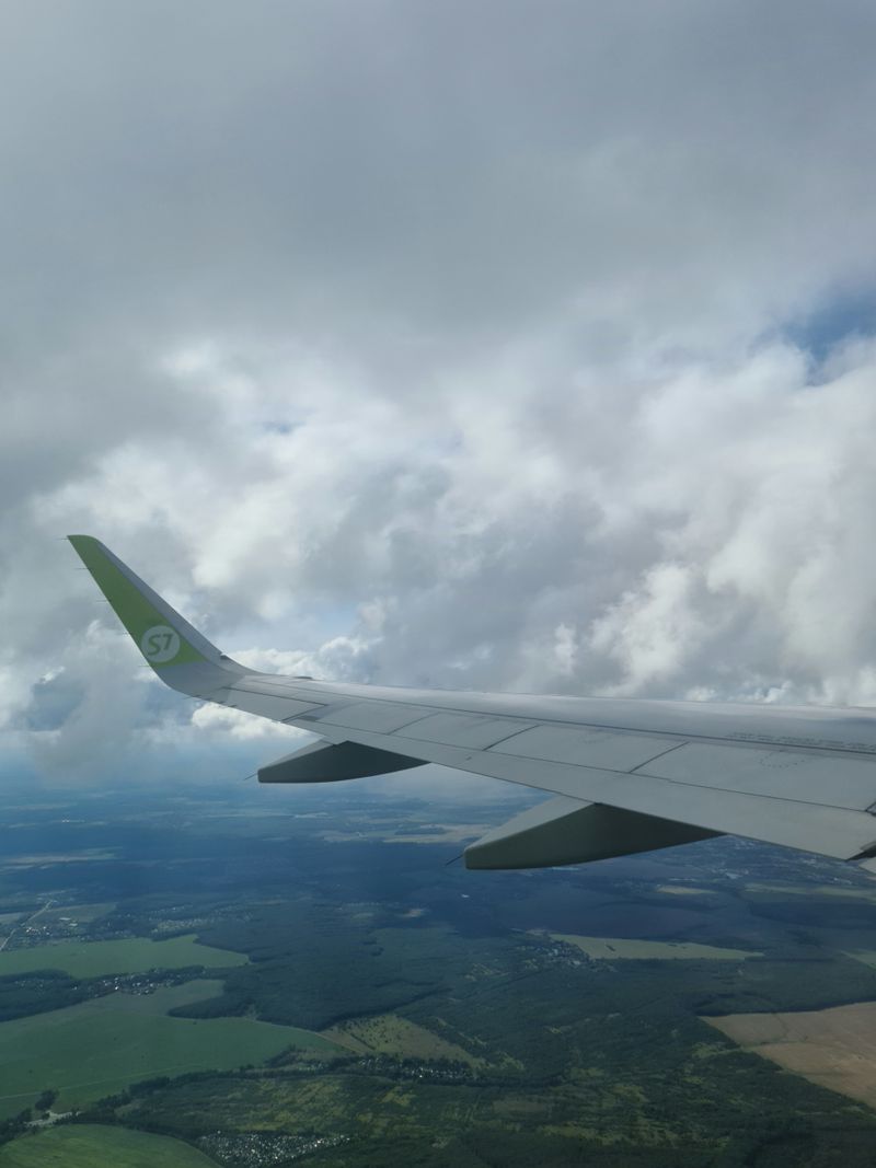 Sayap pesawat di atas awan saat penerbangan internasional