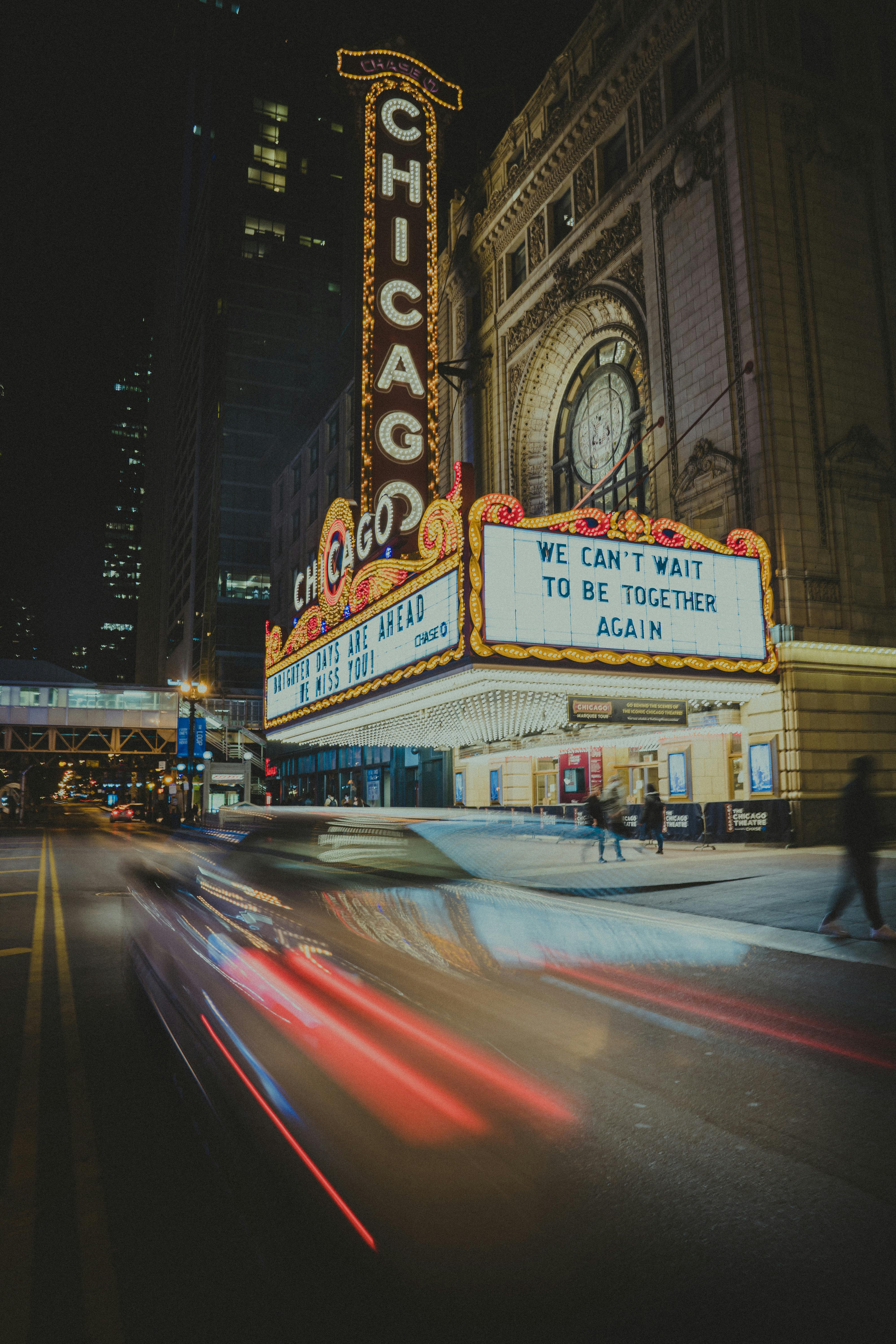 Free A nighttime view of the iconic Chicago Theater with light trails from passing cars. Stock Photo