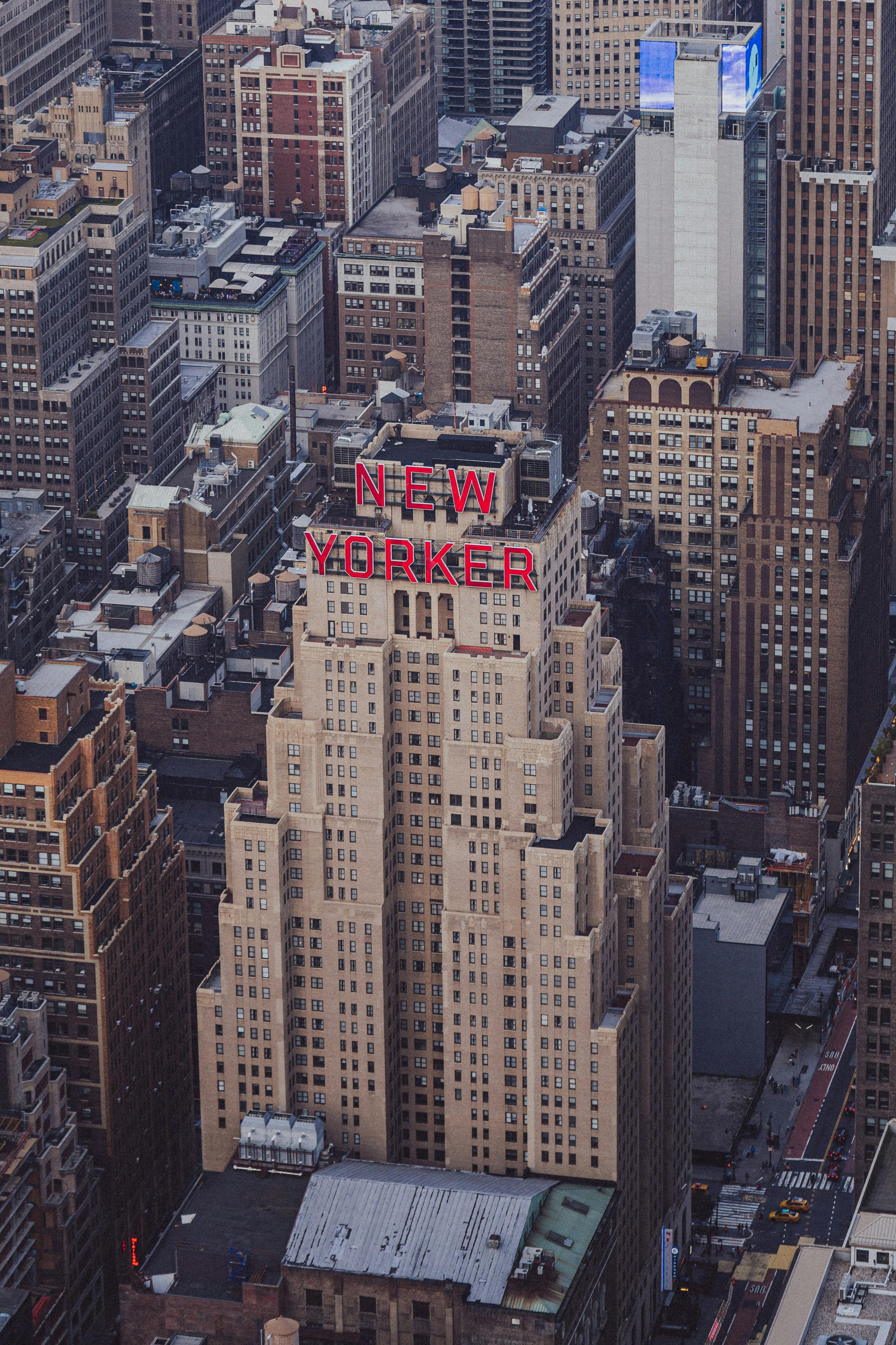 High-angle aerial shot of the iconic New Yorker Hotel amidst skyscrapers in Manhattan.