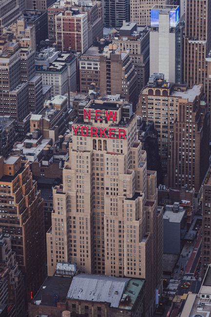 High-angle aerial shot of the iconic New Yorker Hotel amidst skyscrapers in Manhattan.