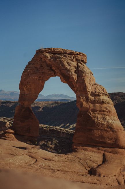 Delicate Arch at golden hour with red rock formations and a clear desert sky