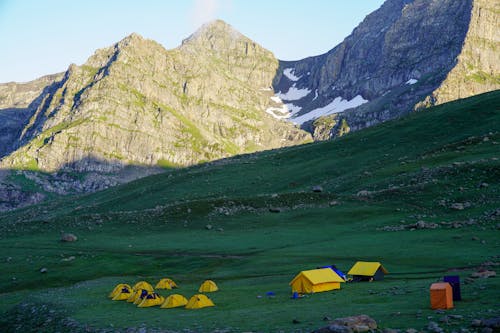 Yellow Tents on Green Grass Near the Mountains