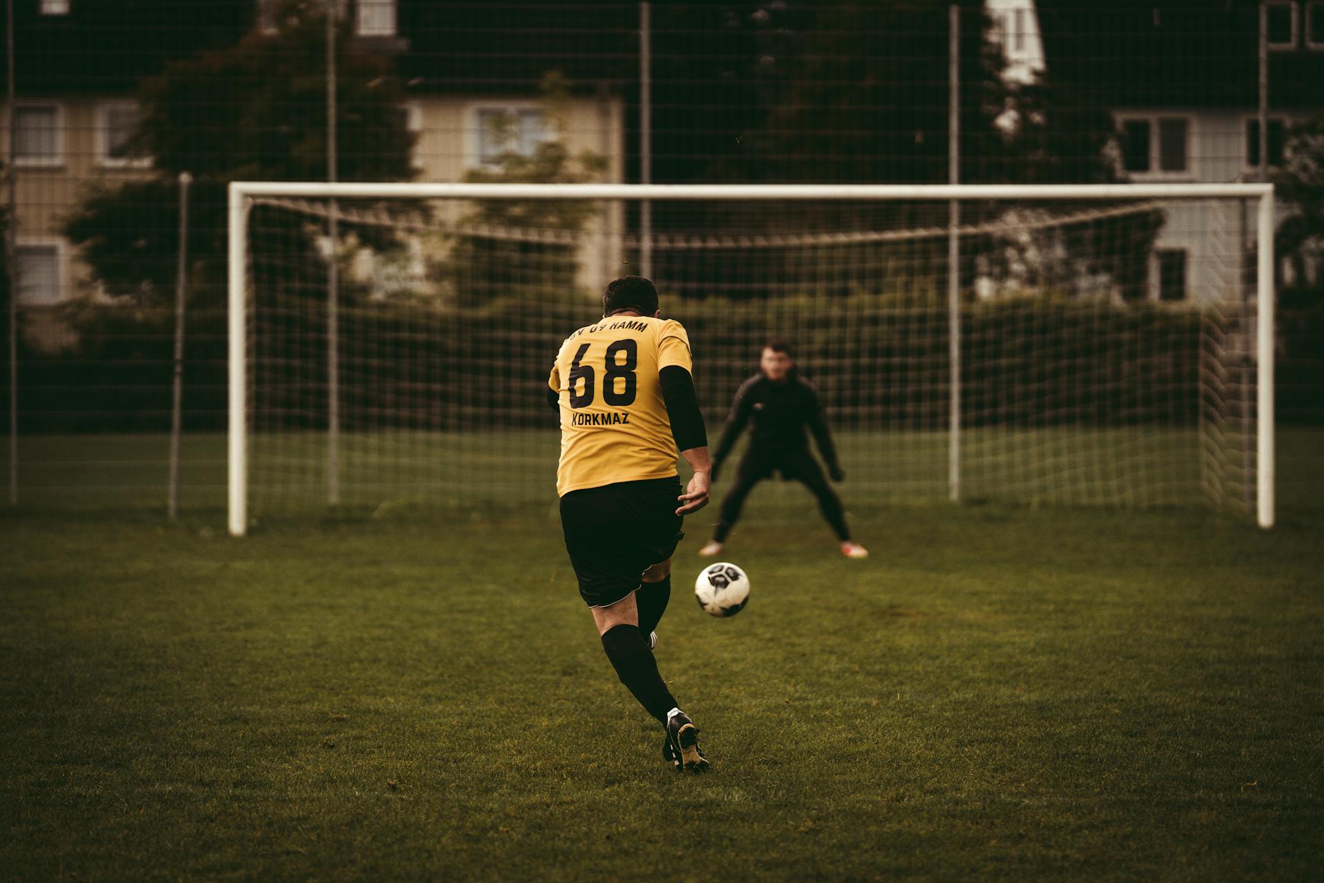 A soccer player takes a decisive penalty kick aiming to score against the goalkeeper.