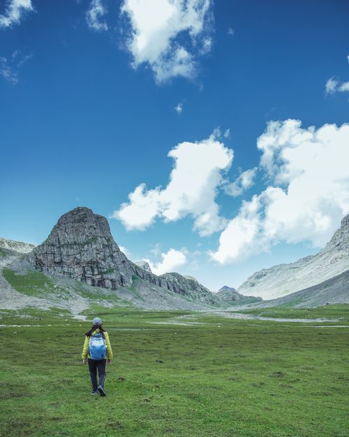 Free A lone hiker with a backpack walks through the picturesque mountains of Shallabugh under a bright blue sky. Stock Photo