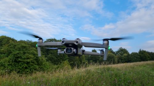 Free Drone in flight over a lush green field with a clear blue sky in Sharpenhoe, England. Stock Photo