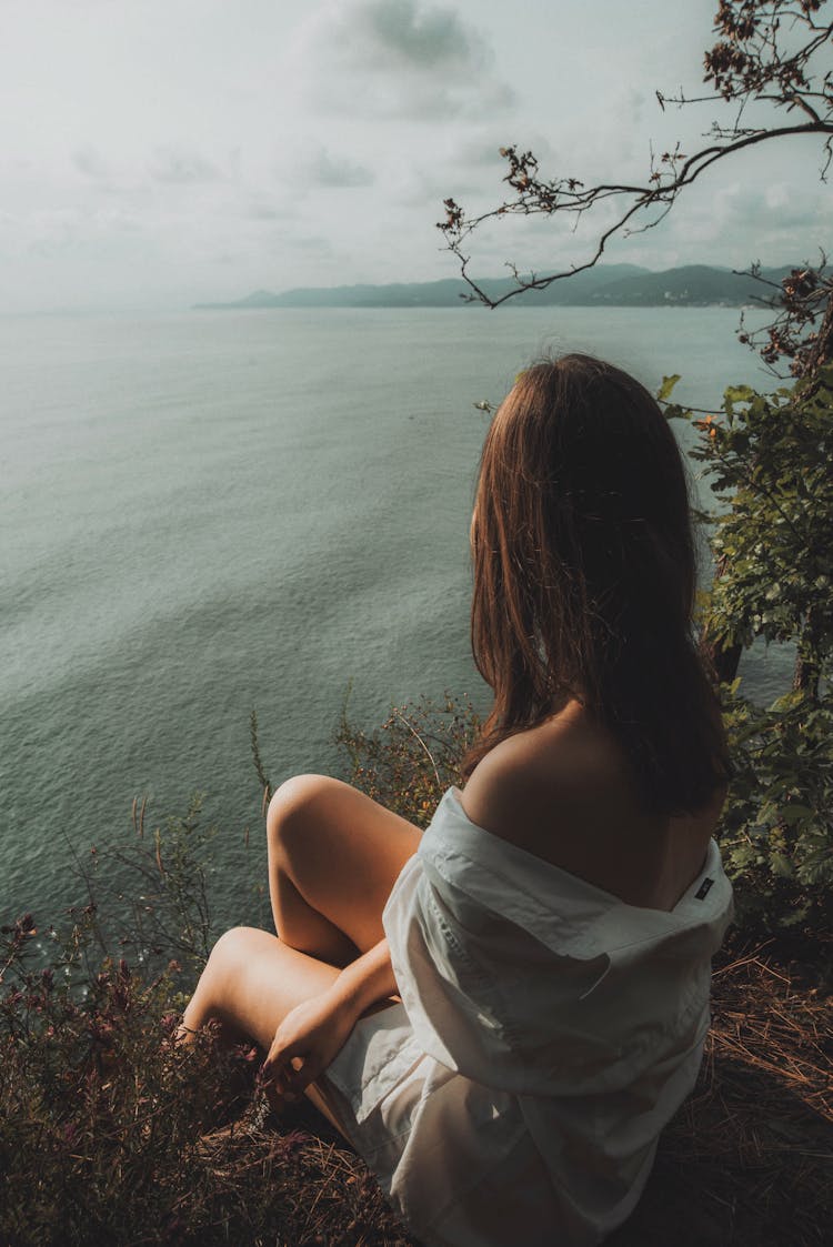 Woman Sitting On Edge Of Cliff