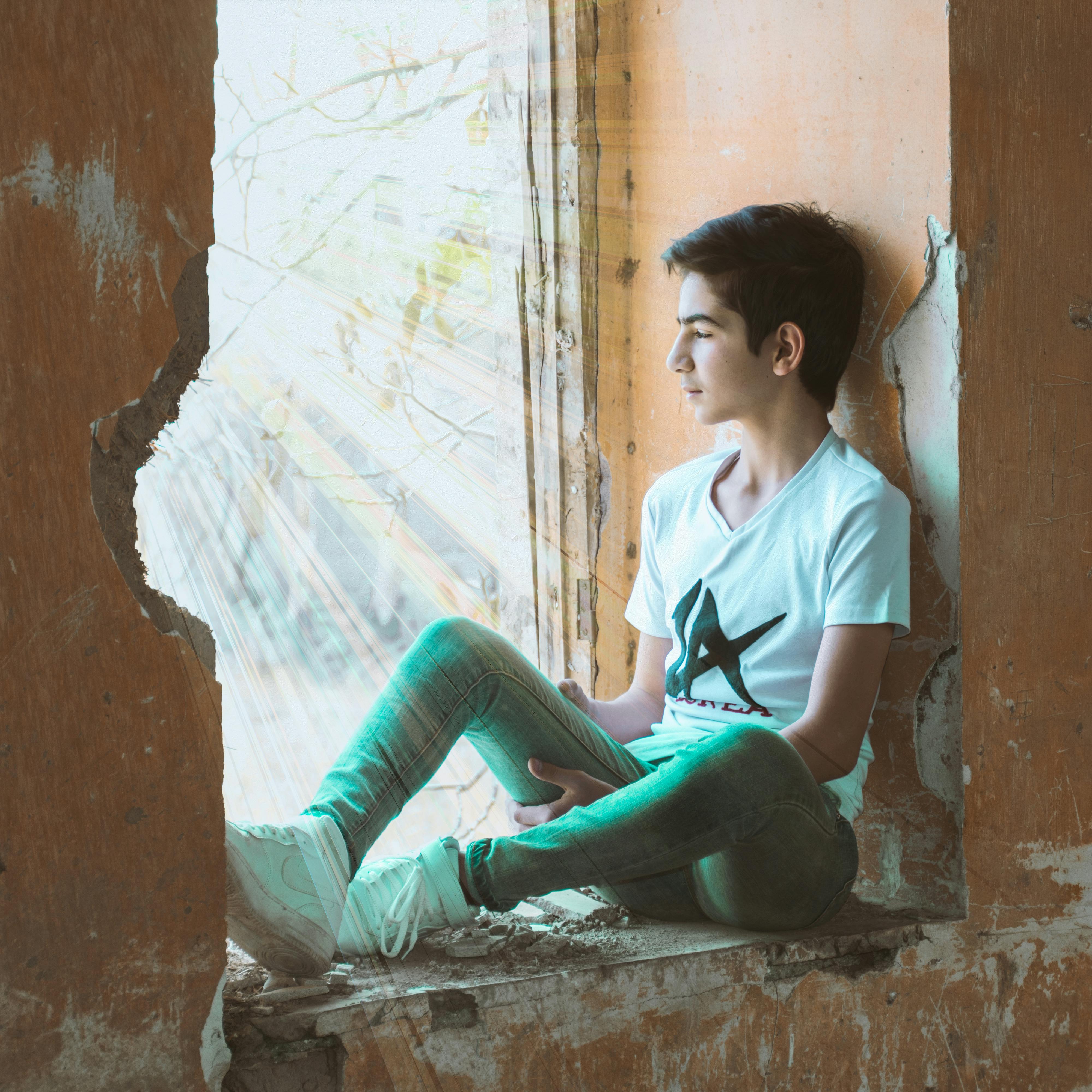 Boy Sitting Near Wall Free Stock Photo