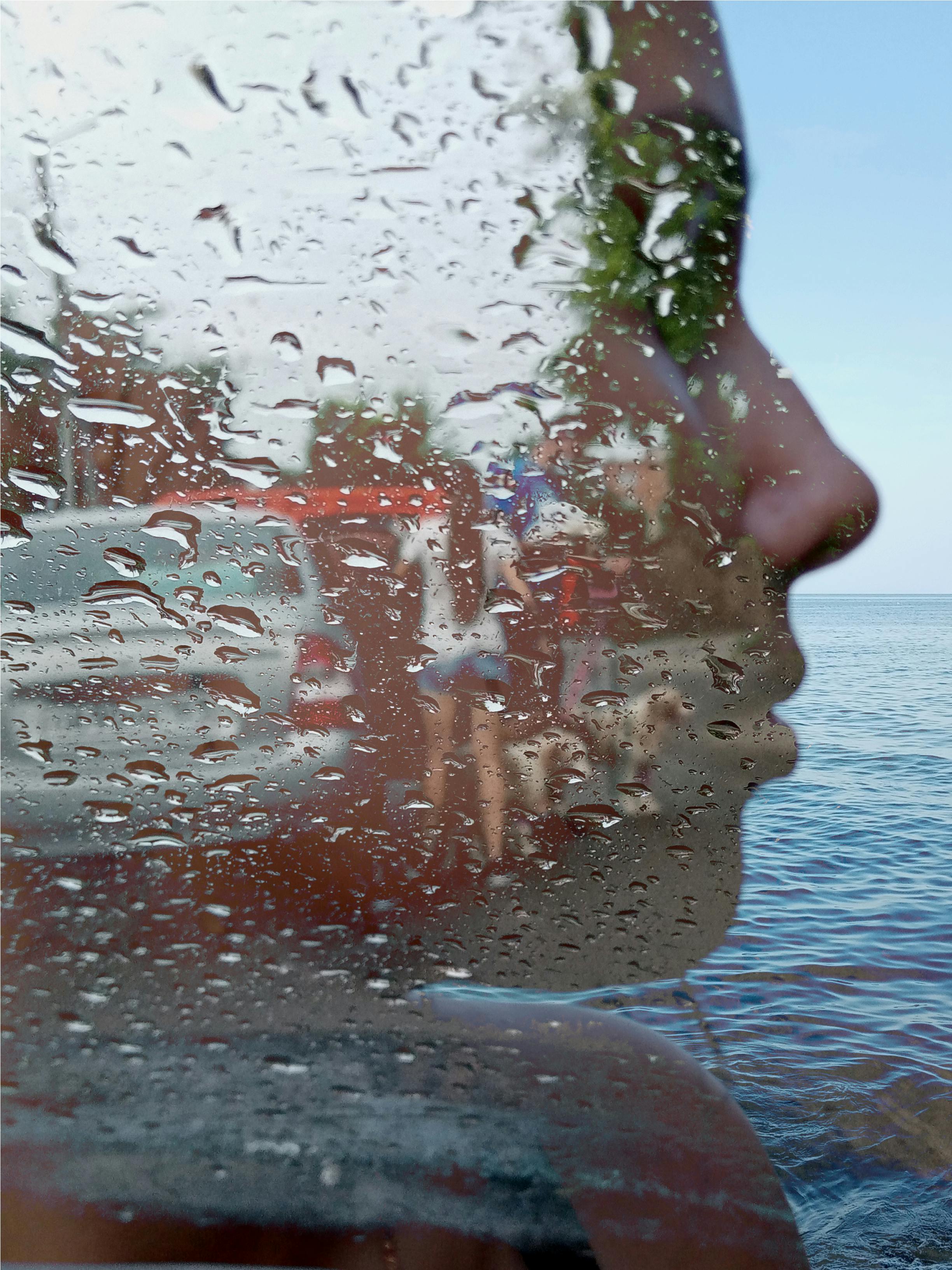 A creative portrait blend showcasing a woman's profile overlaid with raindrops and a seaside backdrop.