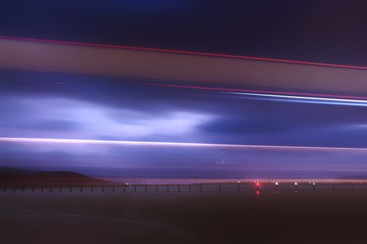 Stunning long exposure night shot capturing vibrant light trails against a moody sky in Scotland.