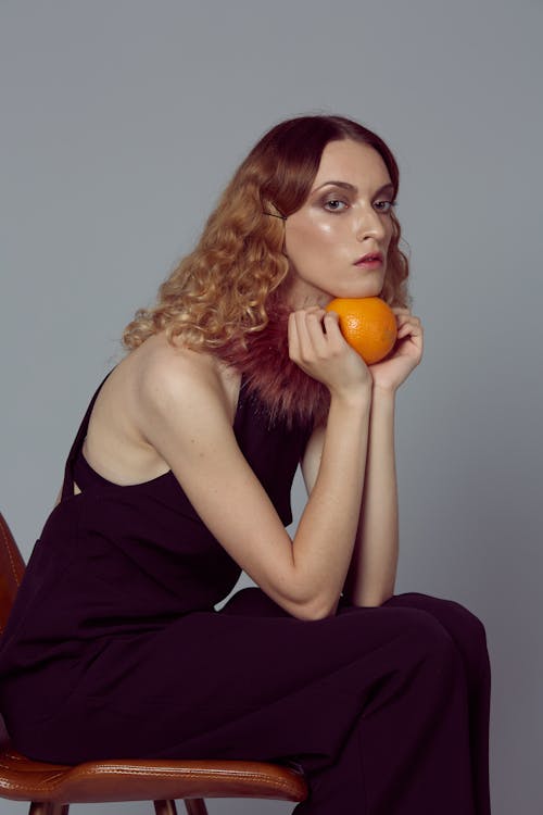 Woman in Black Dress Holding Orange Fruit