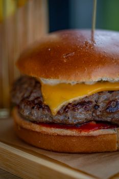 Mouthwatering cheeseburger with juicy beef patty and cheddar cheese served on a wooden board.