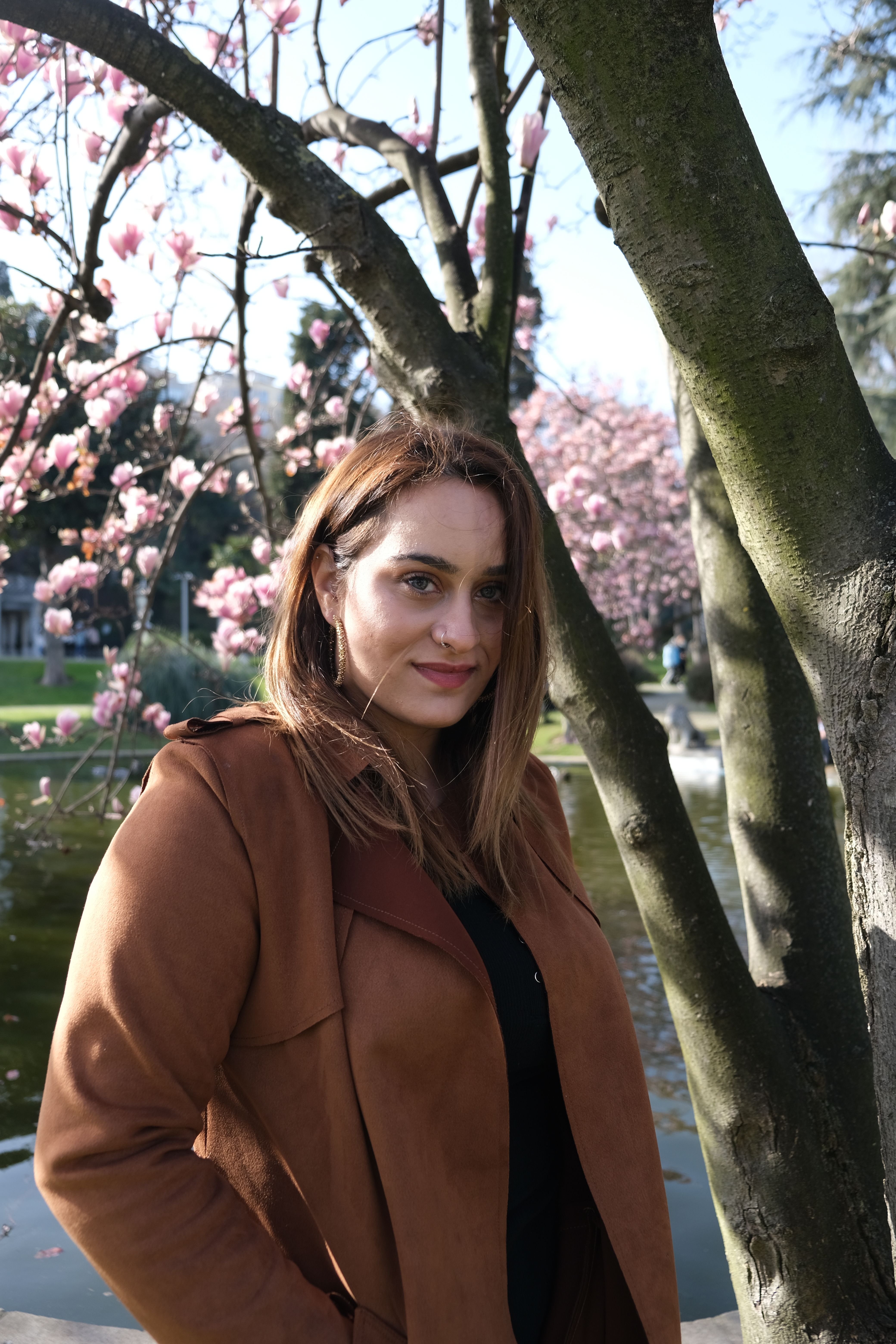 A Woman in Brown Coat Standing Beside Flowering Tree · Free Stock Photo