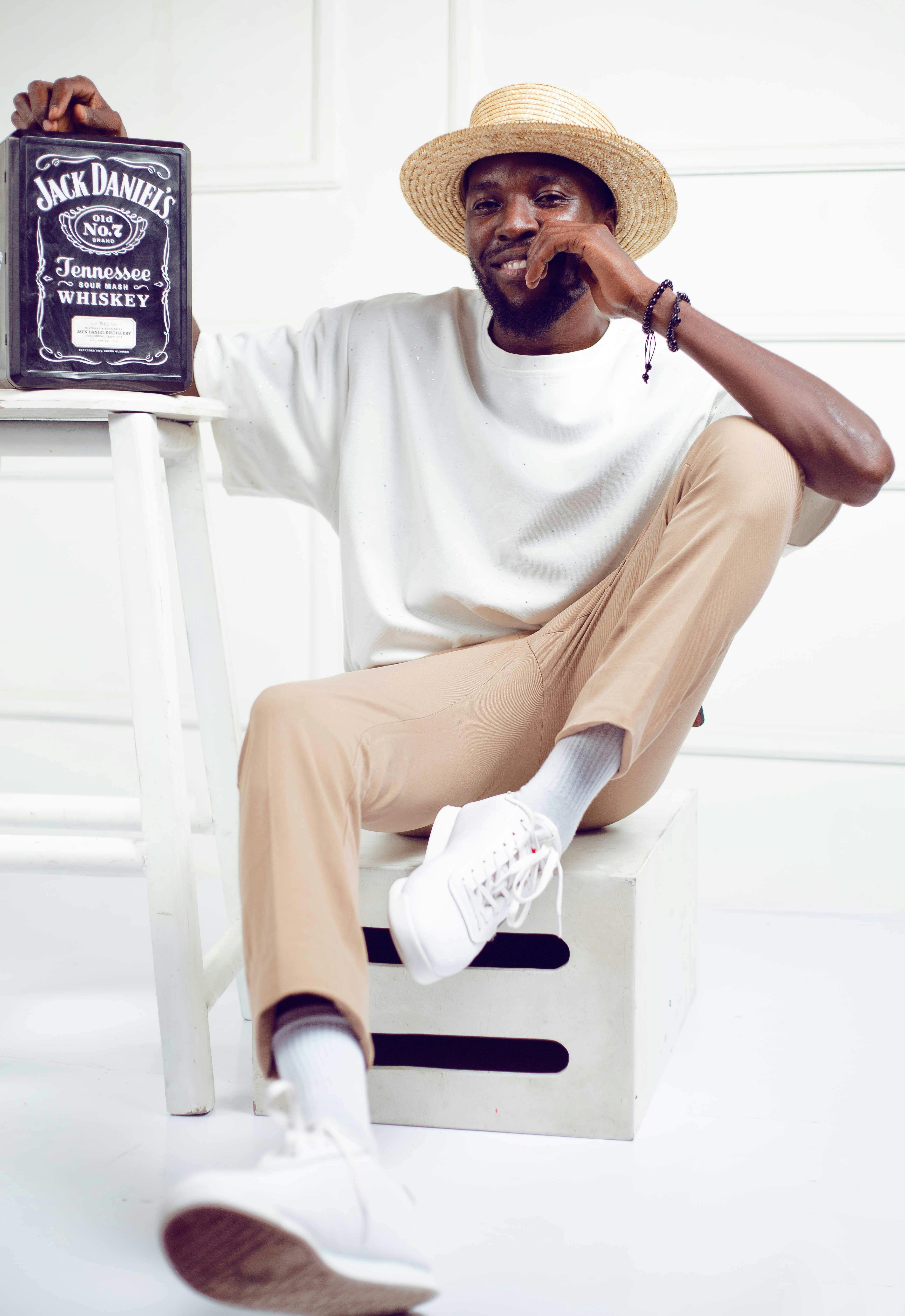 African American man in casual wear sitting indoors with Jack Daniel's whiskey.